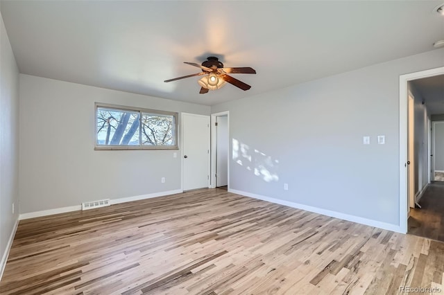 spare room with visible vents, ceiling fan, baseboards, and wood finished floors