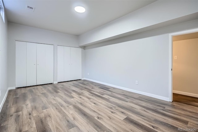 unfurnished bedroom featuring visible vents, multiple closets, and baseboards