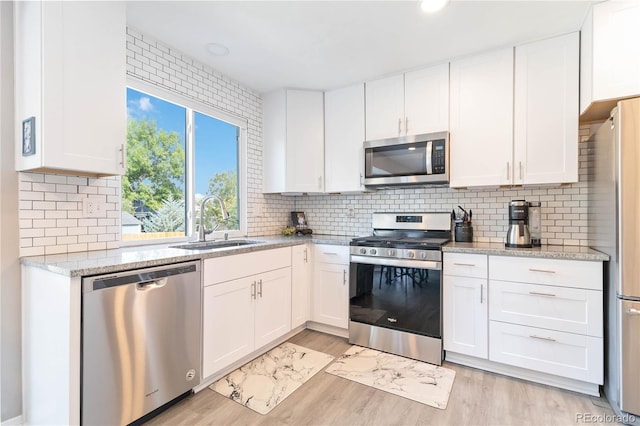 kitchen with white cabinets, decorative backsplash, stainless steel appliances, and sink