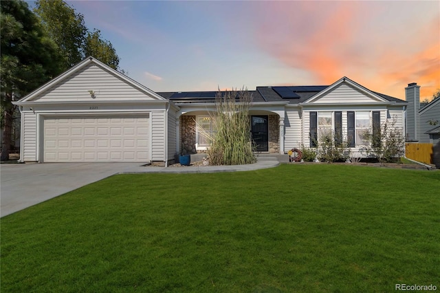 single story home featuring a lawn, a garage, and solar panels