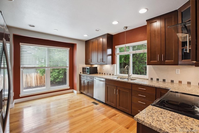 8174 Dudley Cir, Arvada, CO 80005 - kitchen featuring appliances with stainless steel finishes, a sink, light wood-style flooring, light stone countertops, and glass insert cabinets