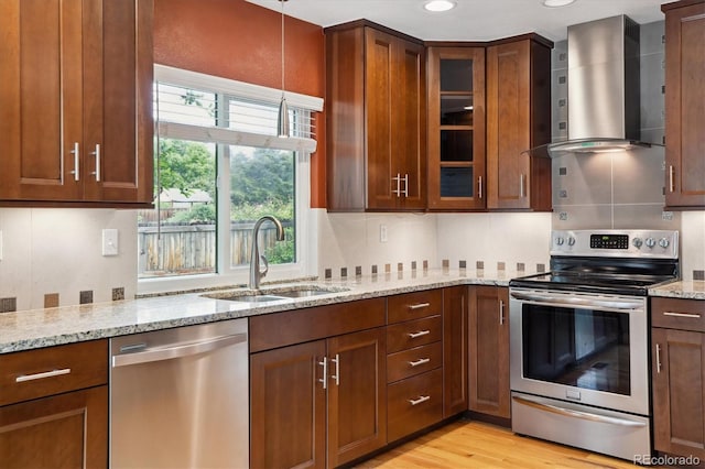 8174 Dudley Cir, Arvada, CO 80005 - kitchen featuring appliances with stainless steel finishes, a sink, wall chimney exhaust hood, light stone counters, and glass insert cabinets