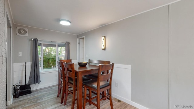 dining space with ornamental molding and light hardwood / wood-style flooring