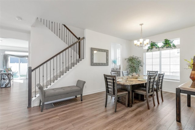 dining space with light hardwood / wood-style flooring and an inviting chandelier