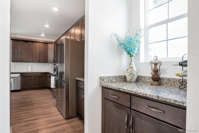 kitchen with light hardwood / wood-style flooring, stainless steel appliances, dark brown cabinets, and light stone counters