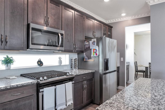 kitchen with light stone counters, dark wood-type flooring, crown molding, dark brown cabinetry, and stainless steel appliances