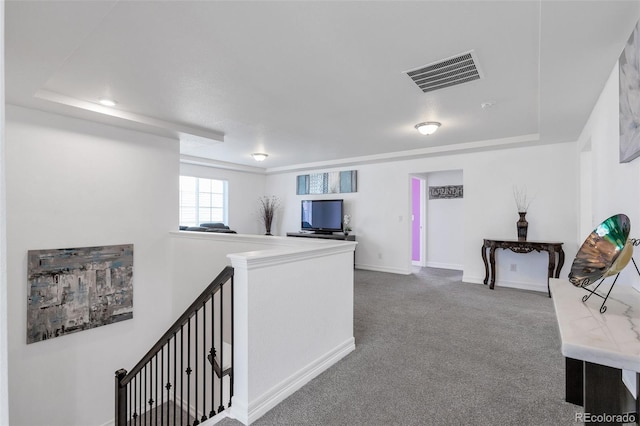 corridor with a raised ceiling and carpet flooring