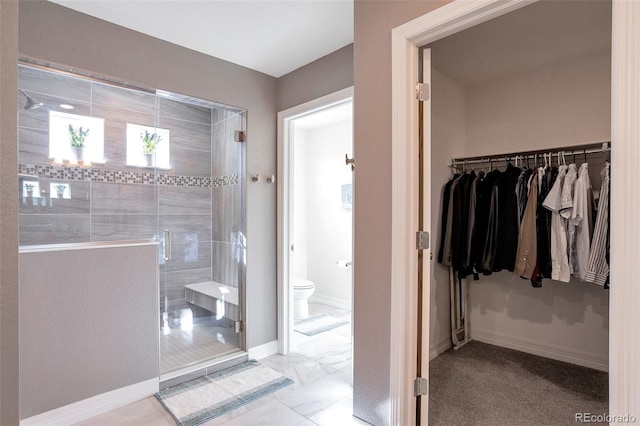 bathroom featuring a shower with door and toilet