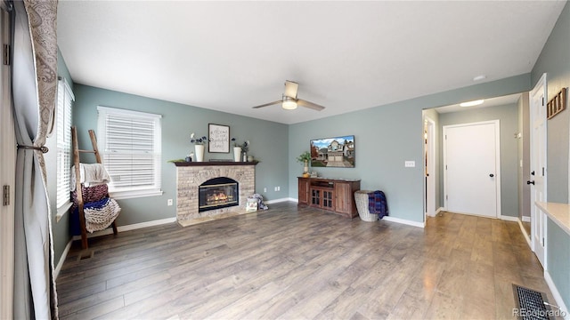 living room featuring hardwood / wood-style floors, ceiling fan, and a brick fireplace