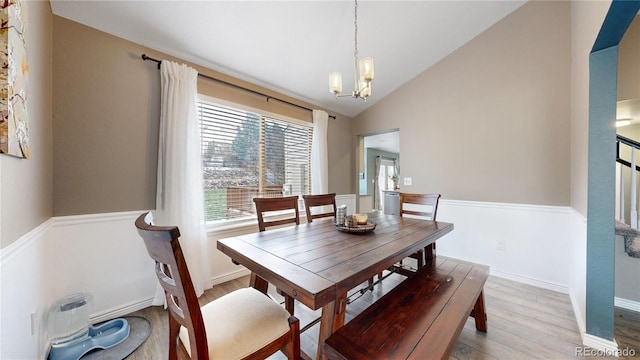 dining area featuring hardwood / wood-style floors, lofted ceiling, and an inviting chandelier