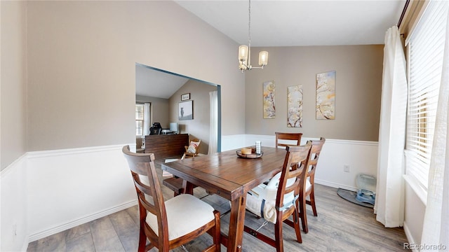 dining area featuring light wood-type flooring, an inviting chandelier, and lofted ceiling