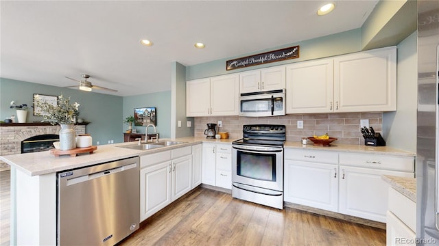 kitchen featuring white cabinets, sink, light hardwood / wood-style flooring, kitchen peninsula, and stainless steel appliances