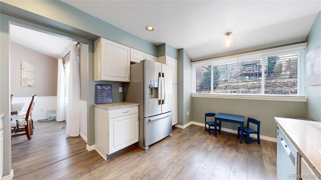 kitchen featuring appliances with stainless steel finishes, white cabinetry, vaulted ceiling, and wood-type flooring