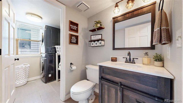 bathroom featuring tile patterned floors, vanity, stacked washing maching and dryer, and toilet