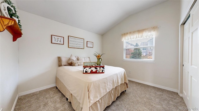 bedroom featuring light colored carpet, lofted ceiling, and a closet