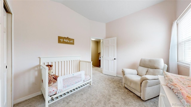 carpeted bedroom with multiple windows, lofted ceiling, a closet, and a crib