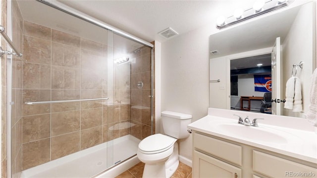 bathroom with tile patterned flooring, vanity, an enclosed shower, and toilet