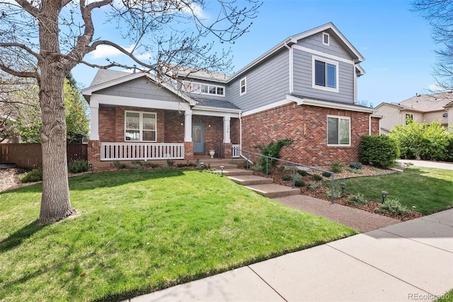 view of front of property featuring fence, a porch, a front lawn, and brick siding