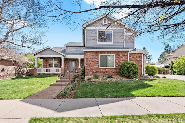 view of front of house with brick siding, a front lawn, and a porch