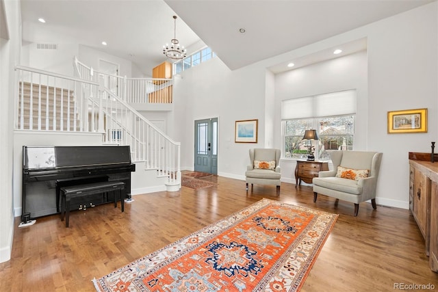 sitting room with baseboards, wood finished floors, a notable chandelier, and stairway