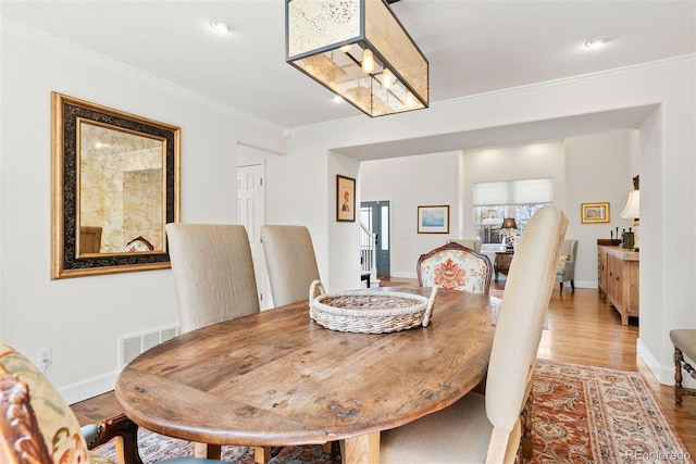 dining room featuring visible vents, wood finished floors, baseboards, ornamental molding, and recessed lighting