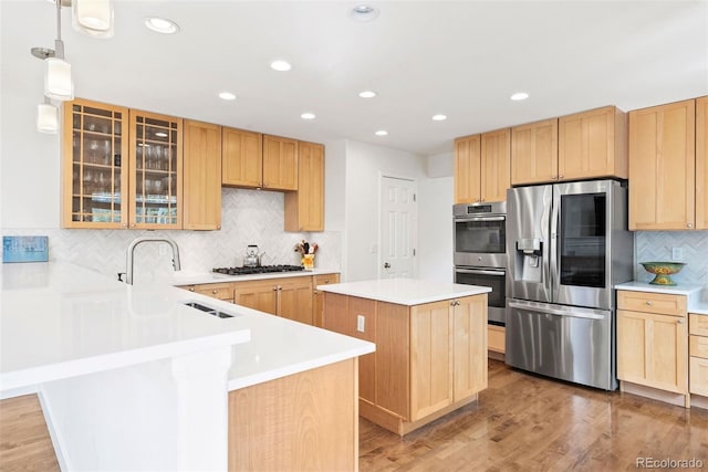 kitchen featuring backsplash, stainless steel appliances, light brown cabinets, and a peninsula