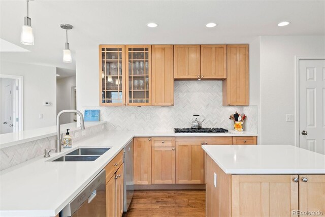 kitchen featuring a sink, dishwasher, a peninsula, decorative backsplash, and gas stovetop