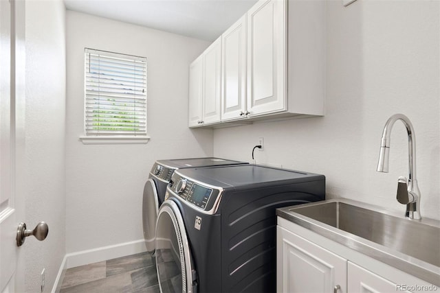clothes washing area featuring washing machine and dryer, baseboards, dark wood finished floors, a sink, and cabinet space