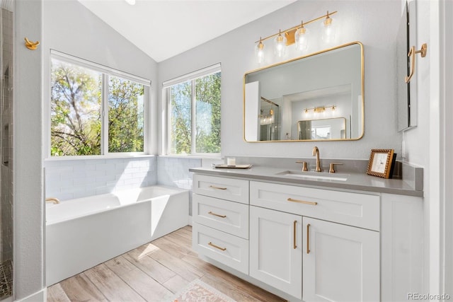 full bathroom with vanity, wood finished floors, lofted ceiling, a shower with door, and a bath