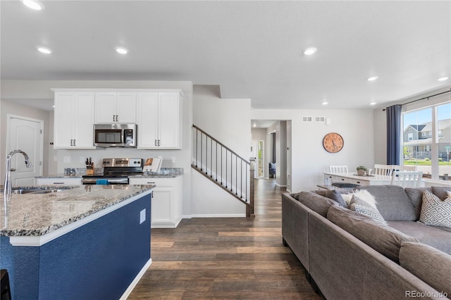 kitchen with dark hardwood / wood-style floors, sink, white cabinets, stainless steel appliances, and light stone countertops