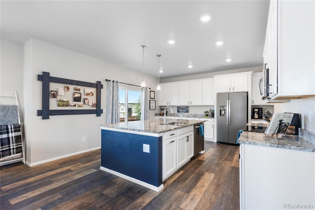 kitchen featuring sink, appliances with stainless steel finishes, hanging light fixtures, white cabinets, and a center island with sink