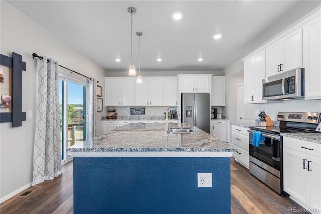 kitchen with stainless steel appliances, decorative light fixtures, sink, and a center island with sink