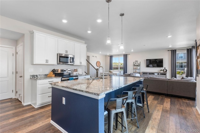 kitchen featuring white cabinetry, sink, stainless steel appliances, and a center island with sink