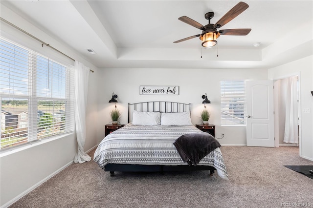 carpeted bedroom with ceiling fan and a tray ceiling