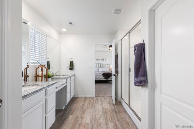 bathroom with vanity, hardwood / wood-style flooring, a shower with shower door, and ceiling fan