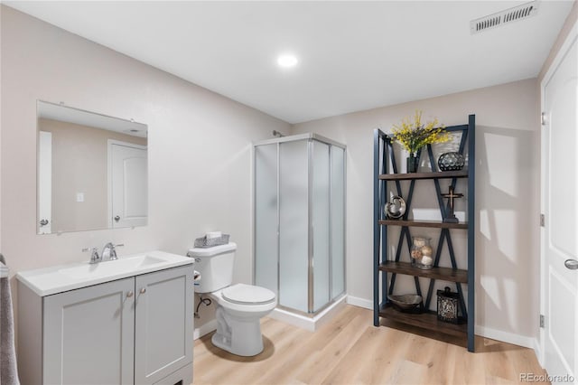 bathroom with vanity, hardwood / wood-style floors, a shower with door, and toilet