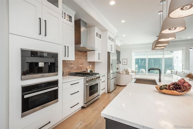 10252 E 58th Ave, Denver, CO 80238 - kitchen featuring stainless steel appliances, wall chimney range hood, tasteful backsplash, open floor plan, and light wood-style flooring