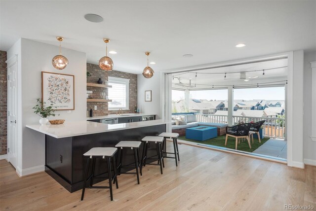 10252 E 58th Ave, Denver, CO 80238 - kitchen with light wood-type flooring, a breakfast bar, a peninsula, open shelves, and hanging light fixtures