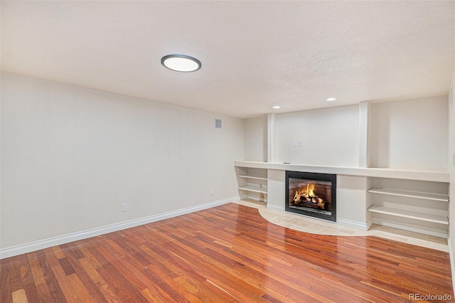 11862 W Stanford Pl, Morrison, CO 80465 - unfurnished living room featuring wood finished floors, a multi sided fireplace, baseboards, recessed lighting, and a textured ceiling