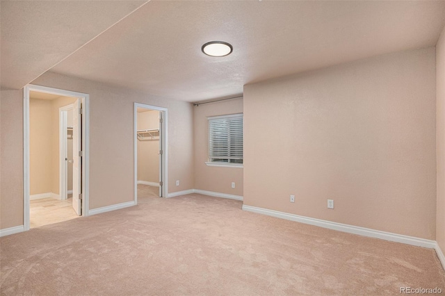 11862 W Stanford Pl, Morrison, CO 80465 - unfurnished bedroom featuring light carpet, a spacious closet, baseboards, a closet, and a textured ceiling