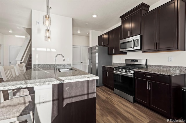 kitchen with sink, appliances with stainless steel finishes, dark hardwood / wood-style floors, a breakfast bar area, and hanging light fixtures