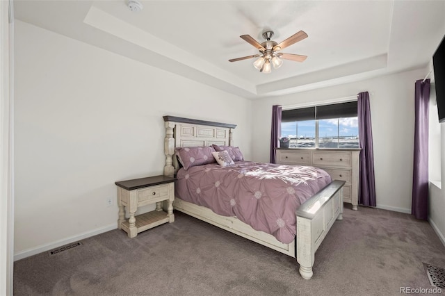 carpeted bedroom with ceiling fan and a tray ceiling