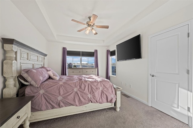 bedroom featuring ceiling fan, light carpet, and a tray ceiling