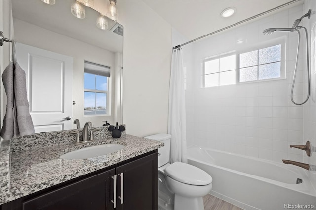 full bathroom featuring hardwood / wood-style floors, vanity, a healthy amount of sunlight, and shower / tub combo