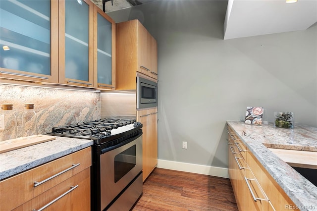 2100 16th St Unit 600, Denver, CO 80202 - kitchen featuring appliances with stainless steel finishes, baseboards, dark wood-type flooring, light stone countertops, and glass insert cabinets