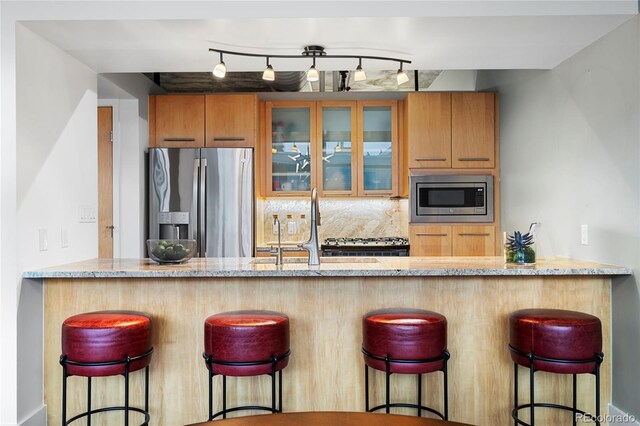 2100 16th St Unit 600, Denver, CO 80202 - kitchen featuring appliances with stainless steel finishes, light stone counters, glass insert cabinets, and decorative backsplash