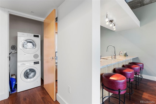 2100 16th St Unit 600, Denver, CO 80202 - washroom featuring stacked washer / dryer, wet bar, dark wood finished floors, and baseboards