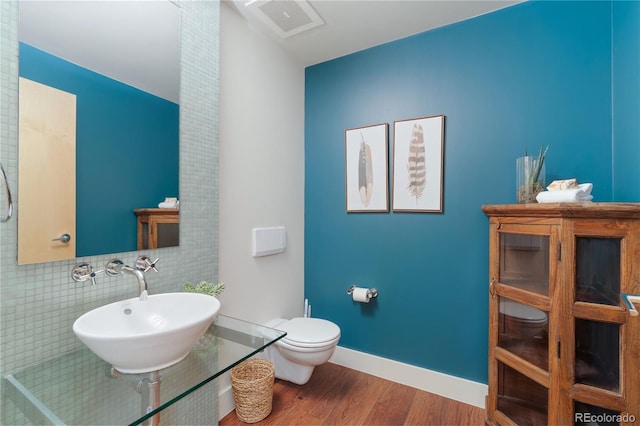 2100 16th St Unit 600, Denver, CO 80202 - bathroom featuring toilet, a sink, wood finished floors, baseboards, and tasteful backsplash