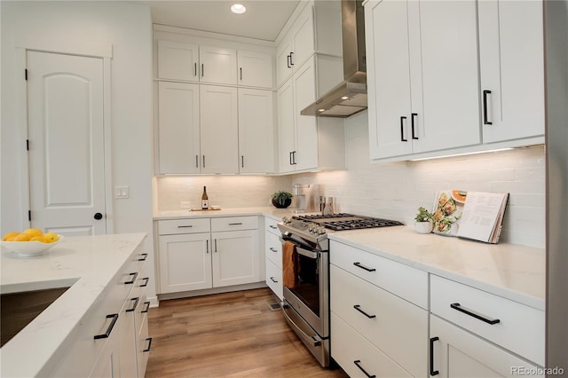 16550 Umatilla Pl, Broomfield, CO 80023 - kitchen with stainless steel gas stove, wall chimney range hood, recessed lighting, white cabinetry, and light stone countertops