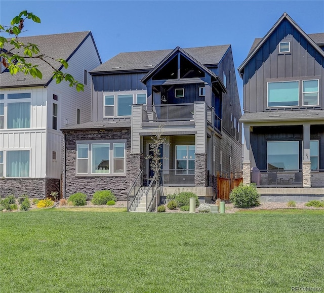 16550 Umatilla Pl, Broomfield, CO 80023 - view of front facade featuring board and batten siding, stone siding, a balcony, and a front yard
